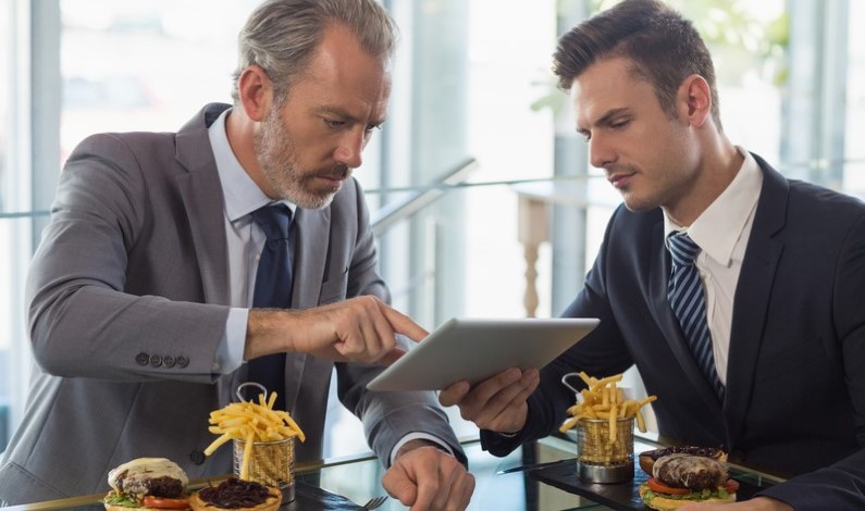 Oameni de afaceri care utilizează o tabletă într-un restaurant