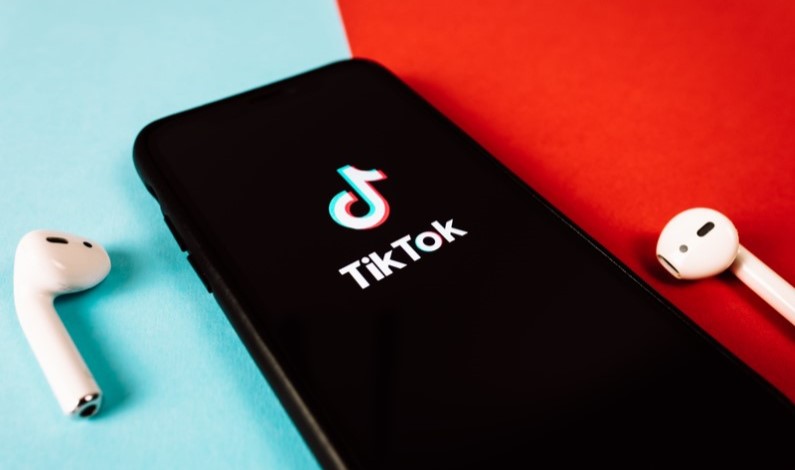 Telefon cu aplicația TikTok și căști wireless