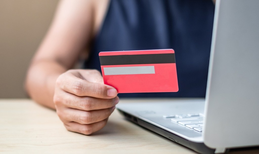 Femeie de afaceri care face cumpărături online pe laptop, ținând un card în mână
